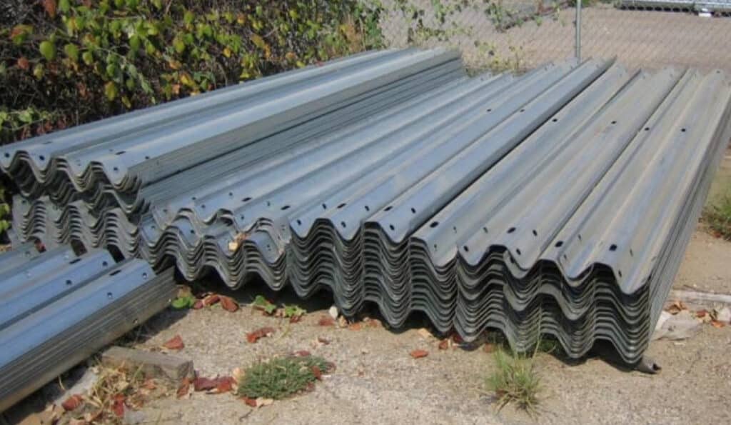 12'-6" W-Beam Metal Beam Guardrail Fence Sections stacked in the yard for storage